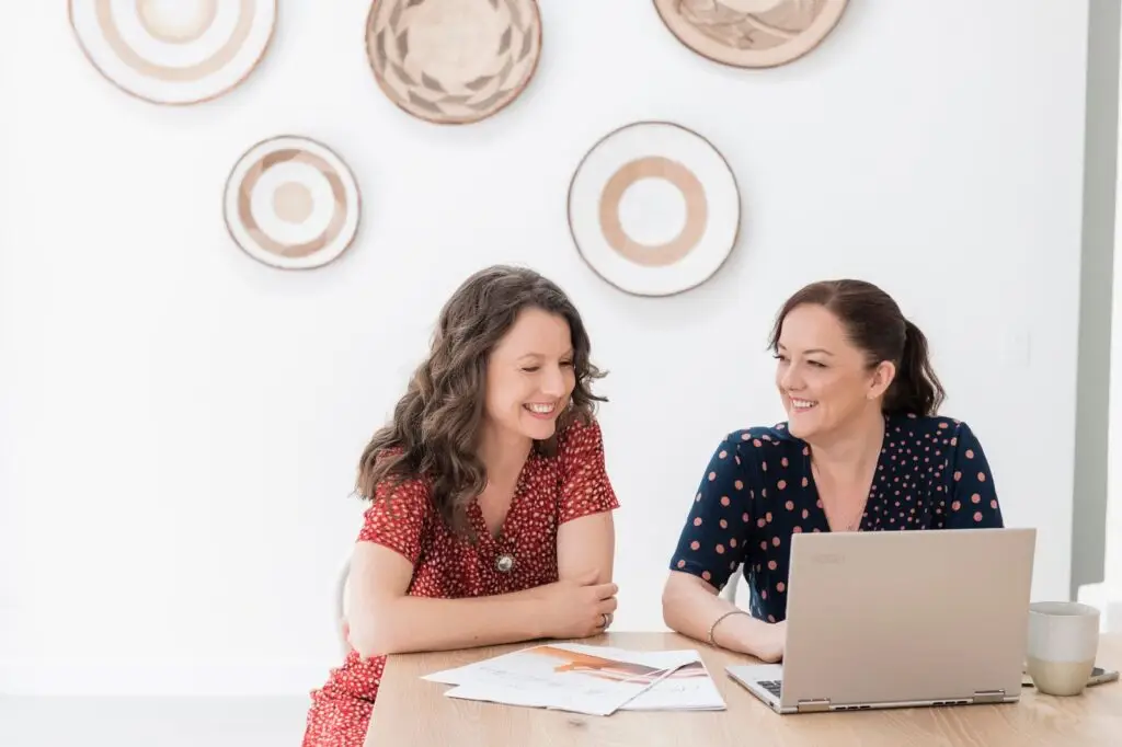 Kym seated with a client beside a laptop
